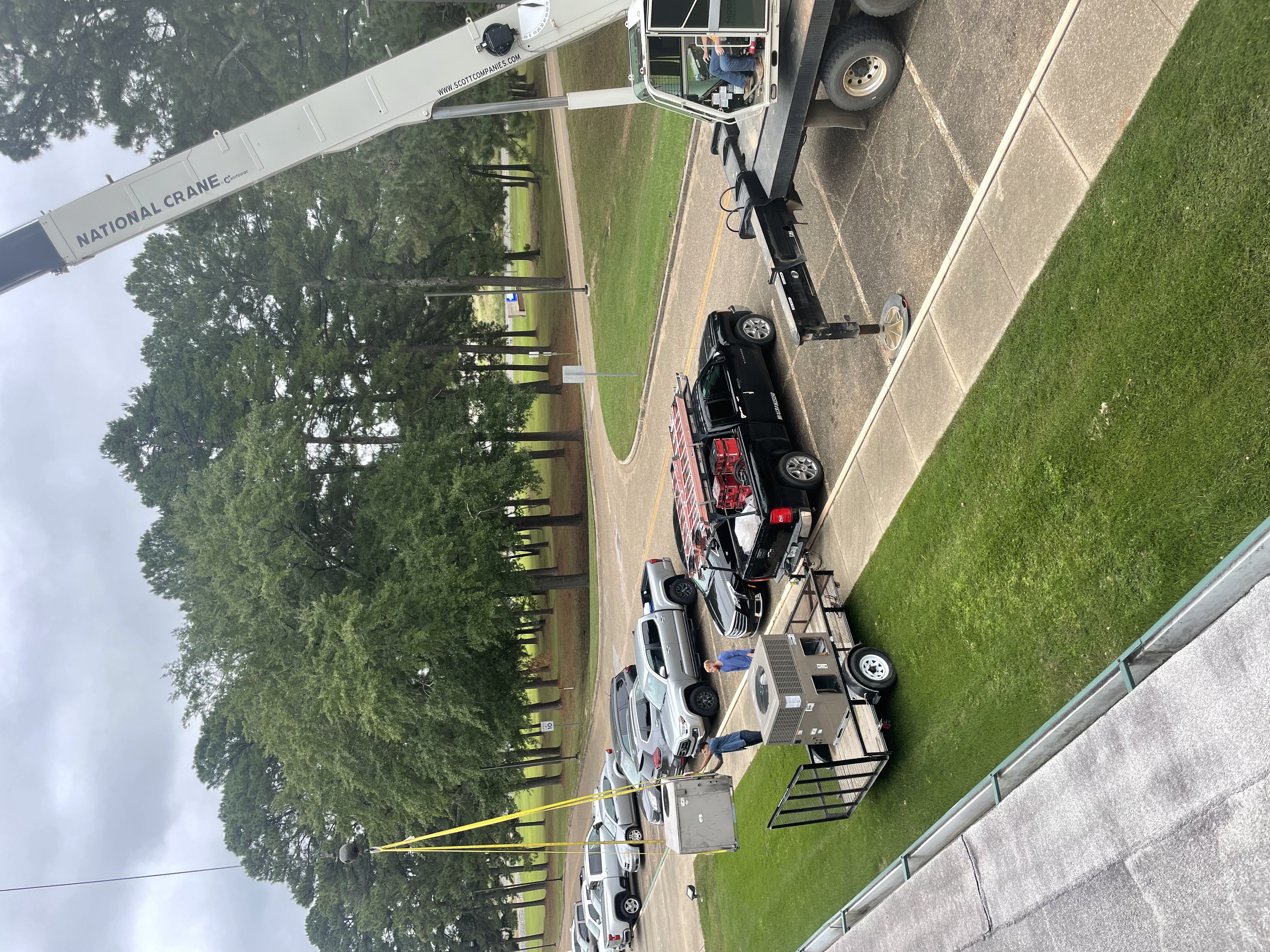 A new packaged rooftop HVAC unit staged on a trailer with a crane set up on a commercial site