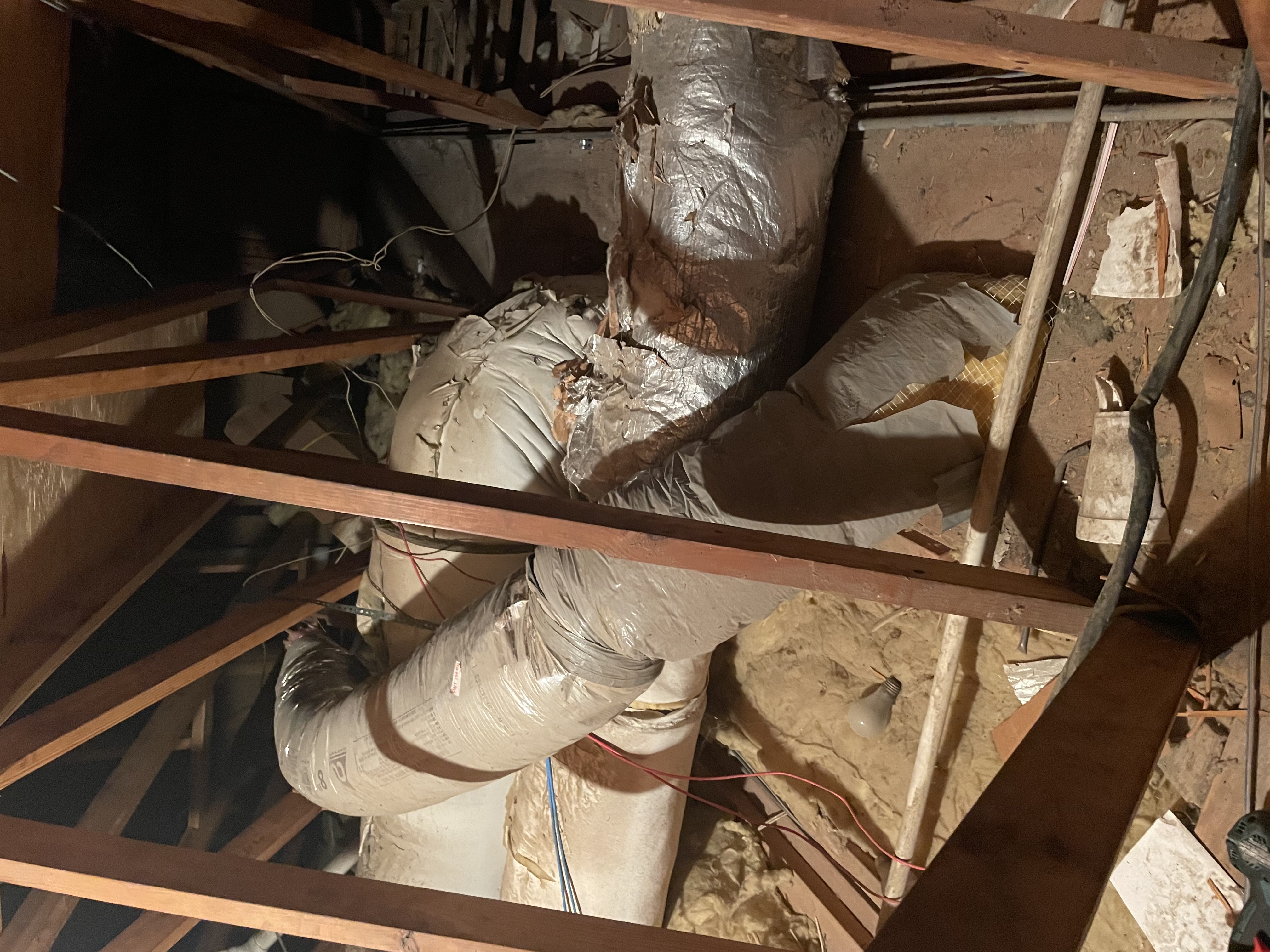 Torn and crushed attic flex ductwork surrounded by debris and loose insulation