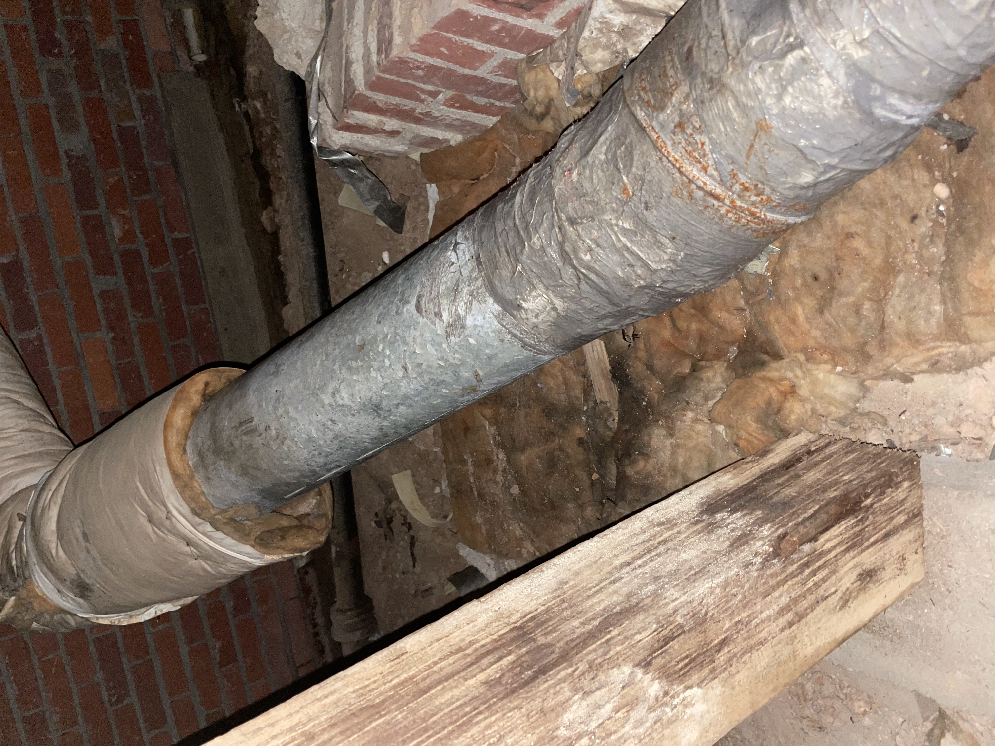 A duct run with insulation fallen away, exposing bare, rusting metal