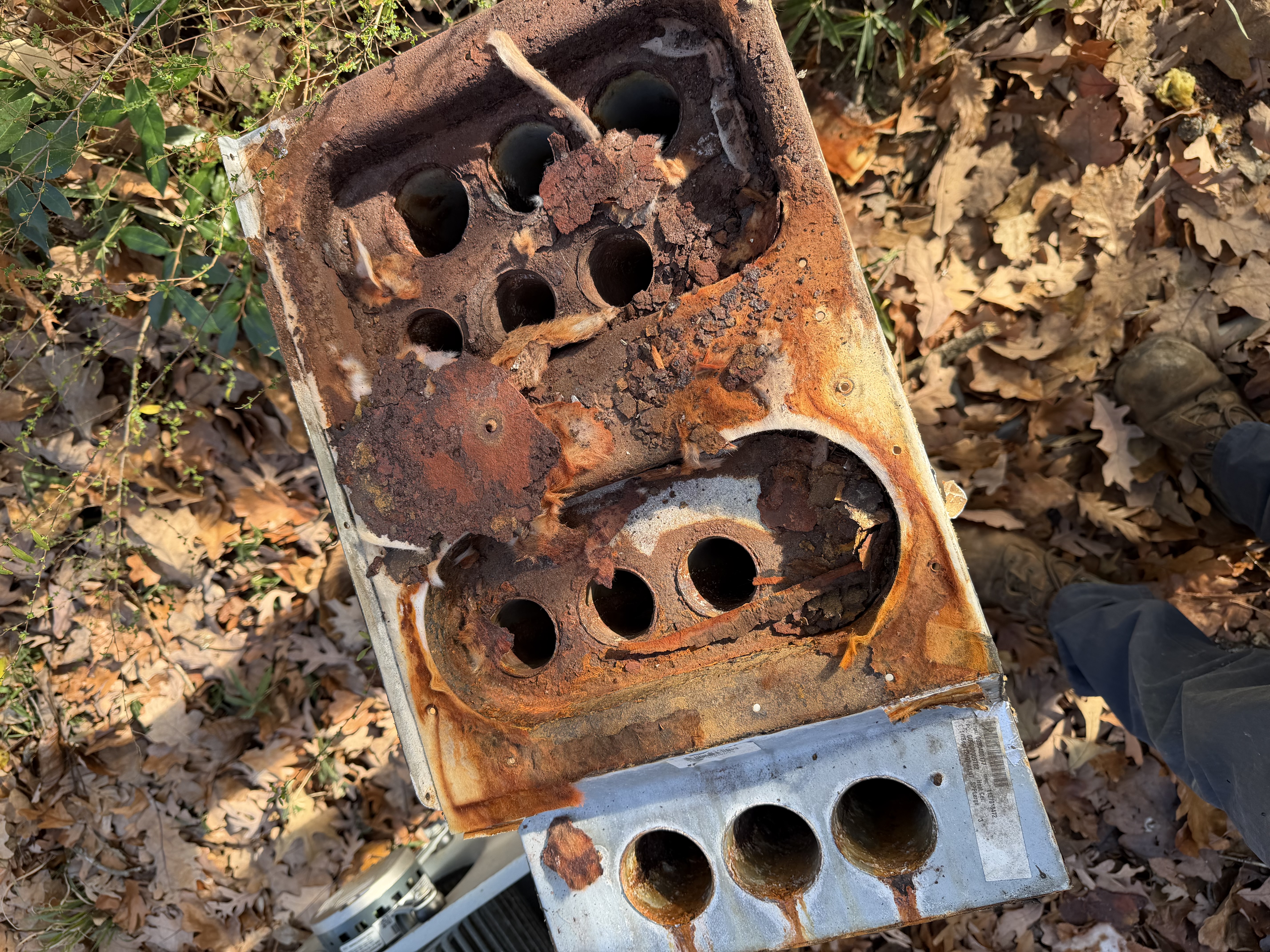 Two heavily rusted furnace heat exchangers removed from service, with rotted-through cells