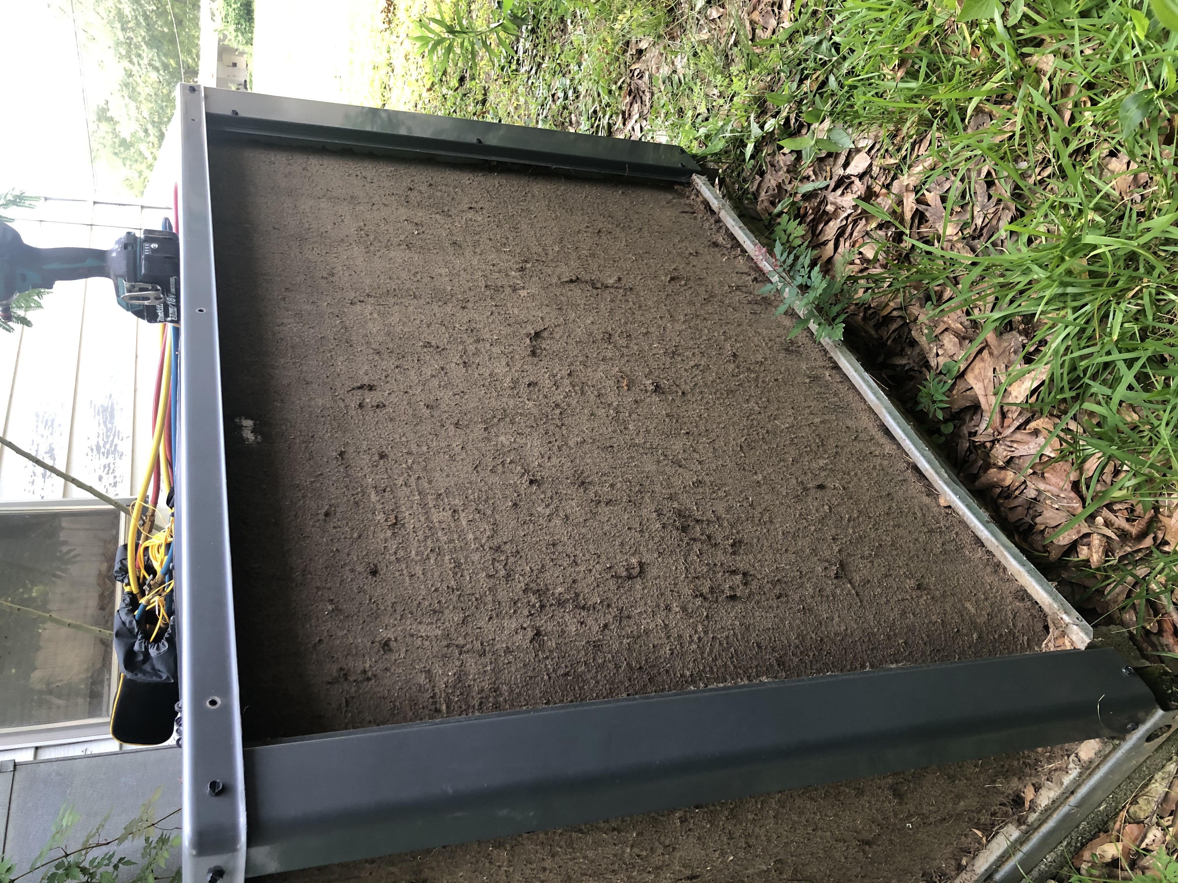 A dirt-caked HVAC condenser coil during a service call, with refrigerant gauges and a drill resting on top of the unit